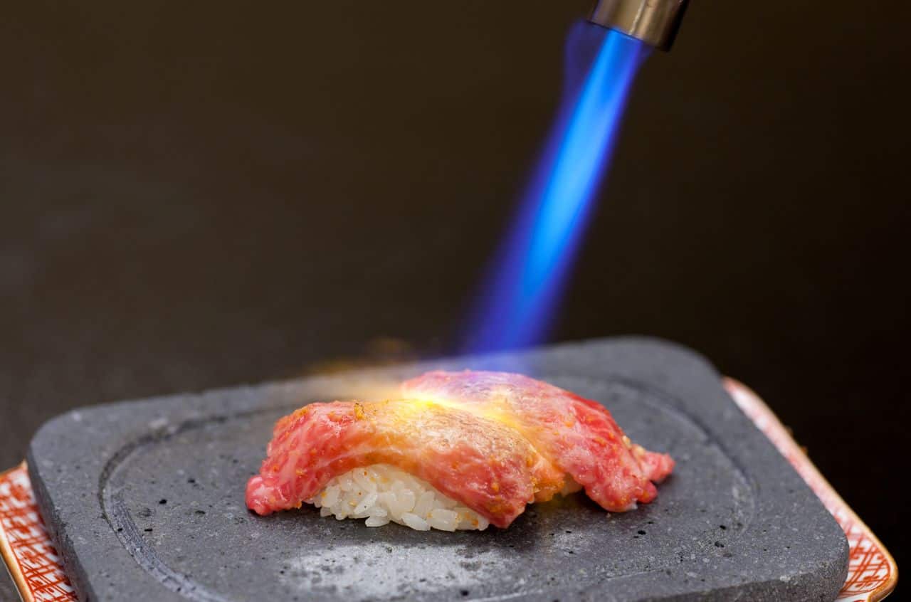 การลนไฟ/อาบุริเพื่อให้เนื้อวัวด้านบนสุก จนเกิดเป็นซูชิที่กึ่งสุกกึ่งดิบ