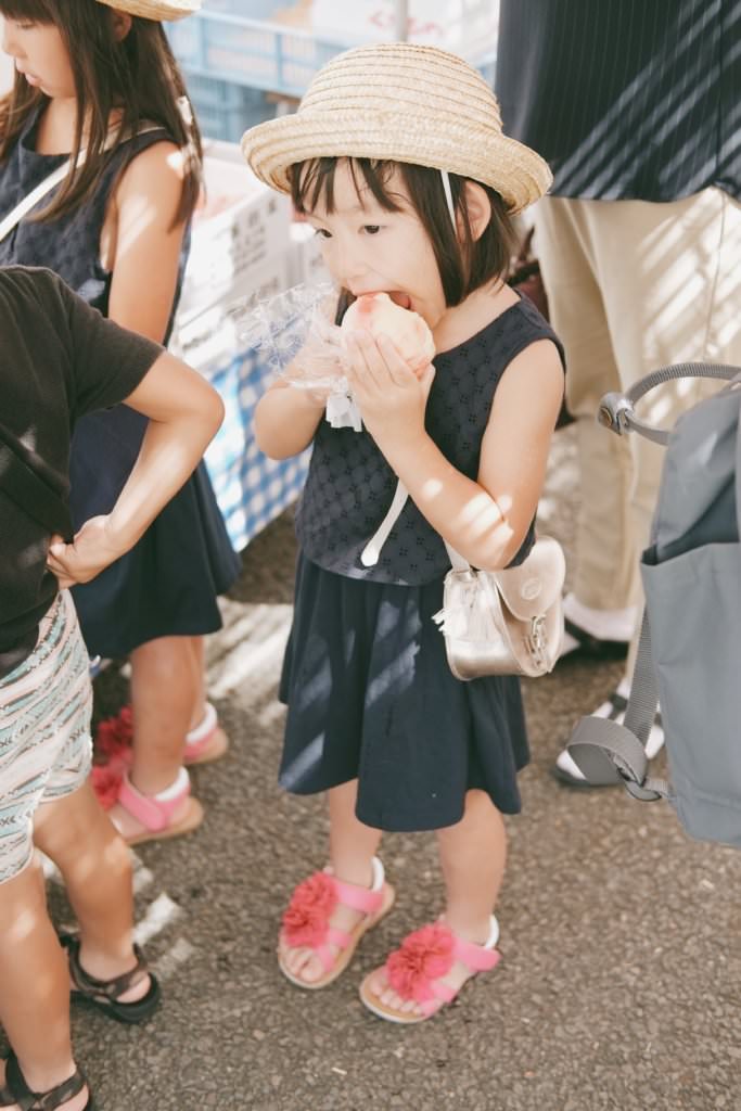 เด็กน้อยกำลังกินลูกพีชหวานฉ่ำของดีในตลาดเช้าจินยะมาเอะ