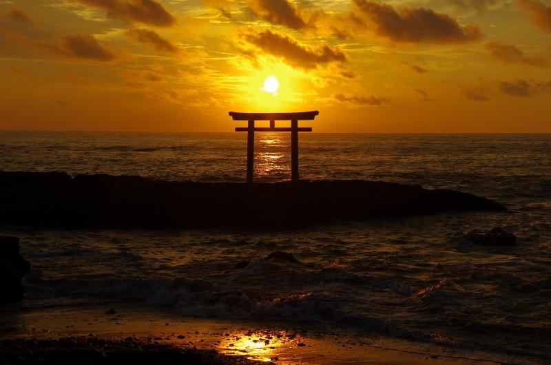 พระอาทิตย์อัสดงที่กำลังจะลับขอบฟ้าเหนือซุ้มประตูโทริอิ (Torii)